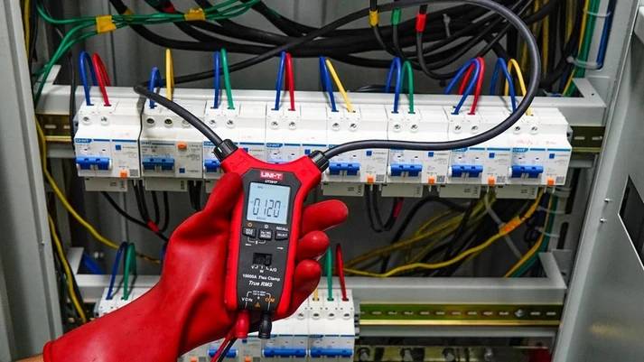 Die flexible Messschleife der UNI-T UT281F Stromzange ist um mehrere Kabel über einer Reihe von Sicherungen gelegt.