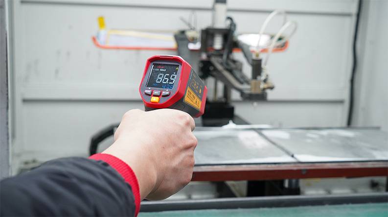 The UNI-T UT305S infrared thermometer being used to monitor the temperature of a machine in a workshop.