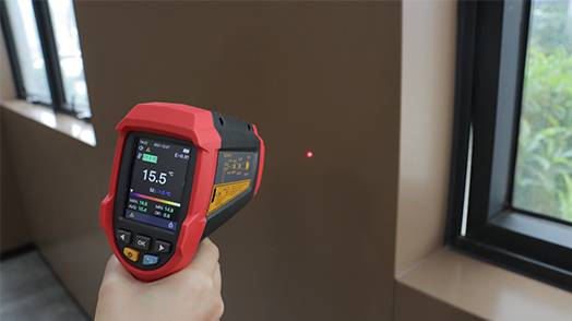 Using the UT305C+ infrared thermometer for precise surface temperature measurement on a wall, ideal for dew point detection and identifying thermal bridges.