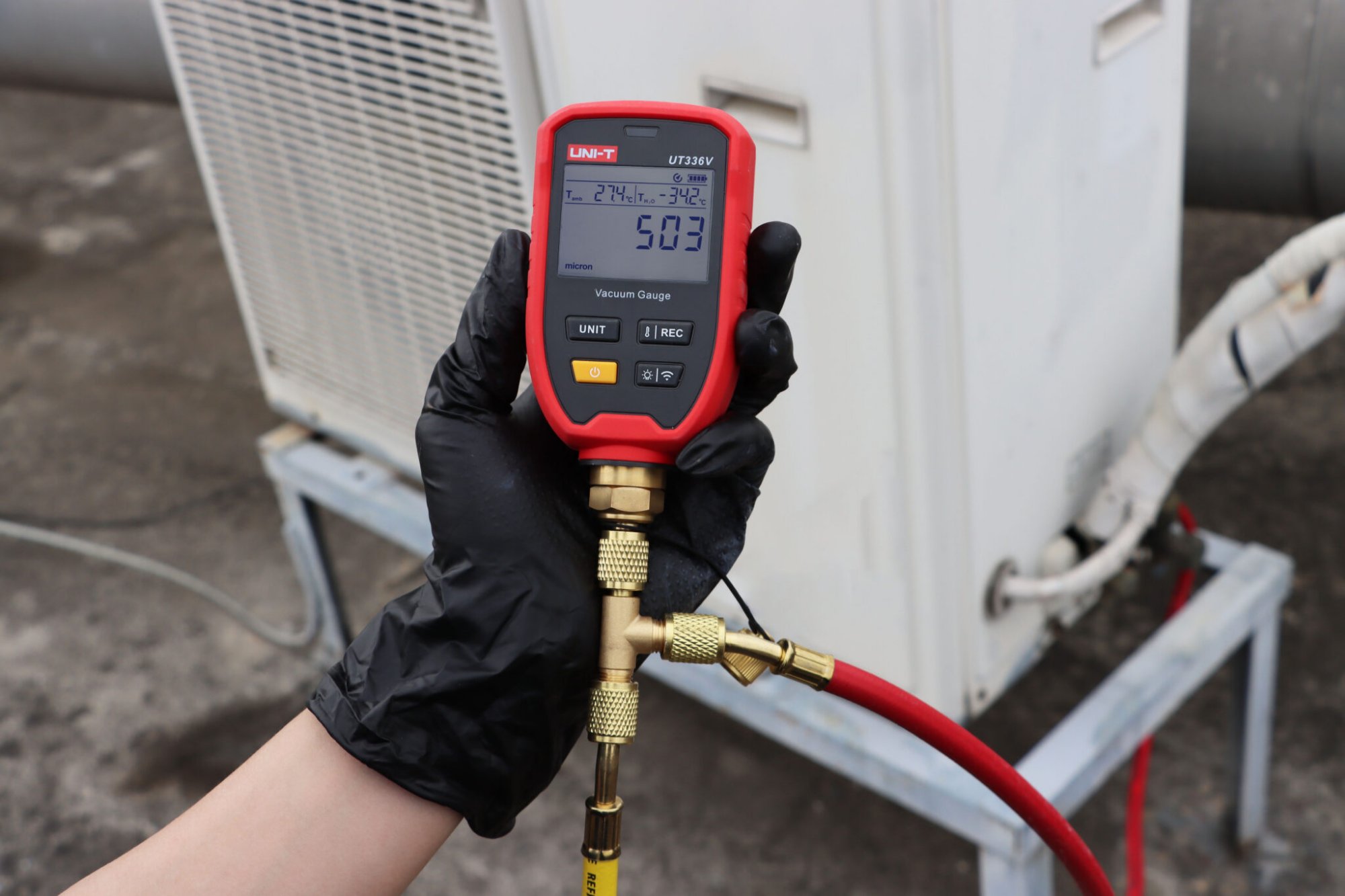 Techniker hält das UNI-T UT336V Vakuummeter bei der Dichtheits- und Evakuierungsmessung an einer Wärmepumpe