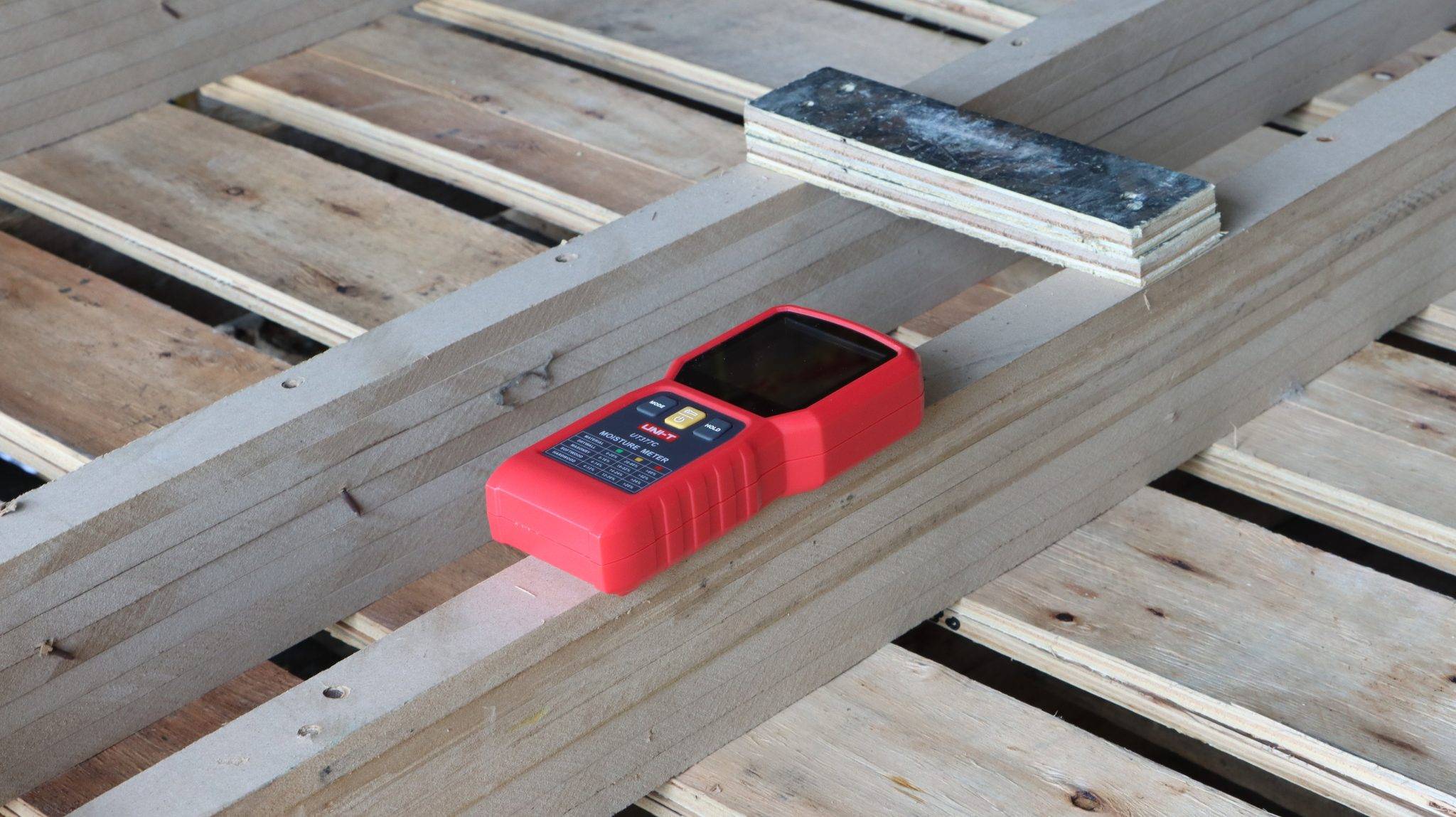 Das UNI-T UT377C Feuchtigkeitsmessgerät liegt auf einer Holzpalette und ist bereit für die Messung von Holzfeuchte.