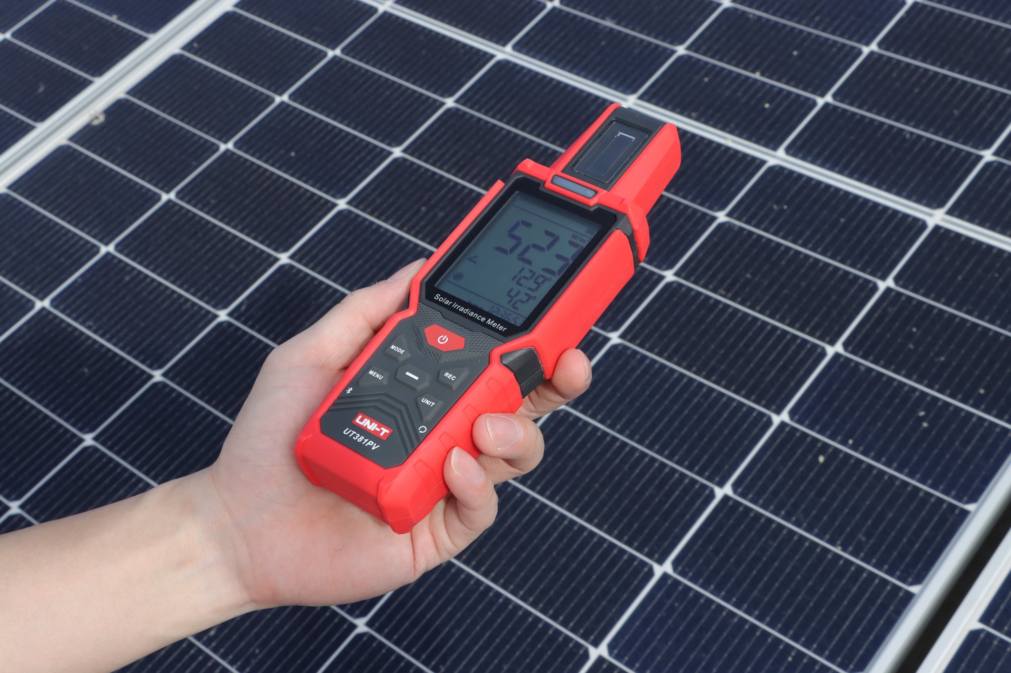 UNI-T UT381PV Solar-Einstrahlungsmessgerät in der Hand vor Photovoltaikmodulen