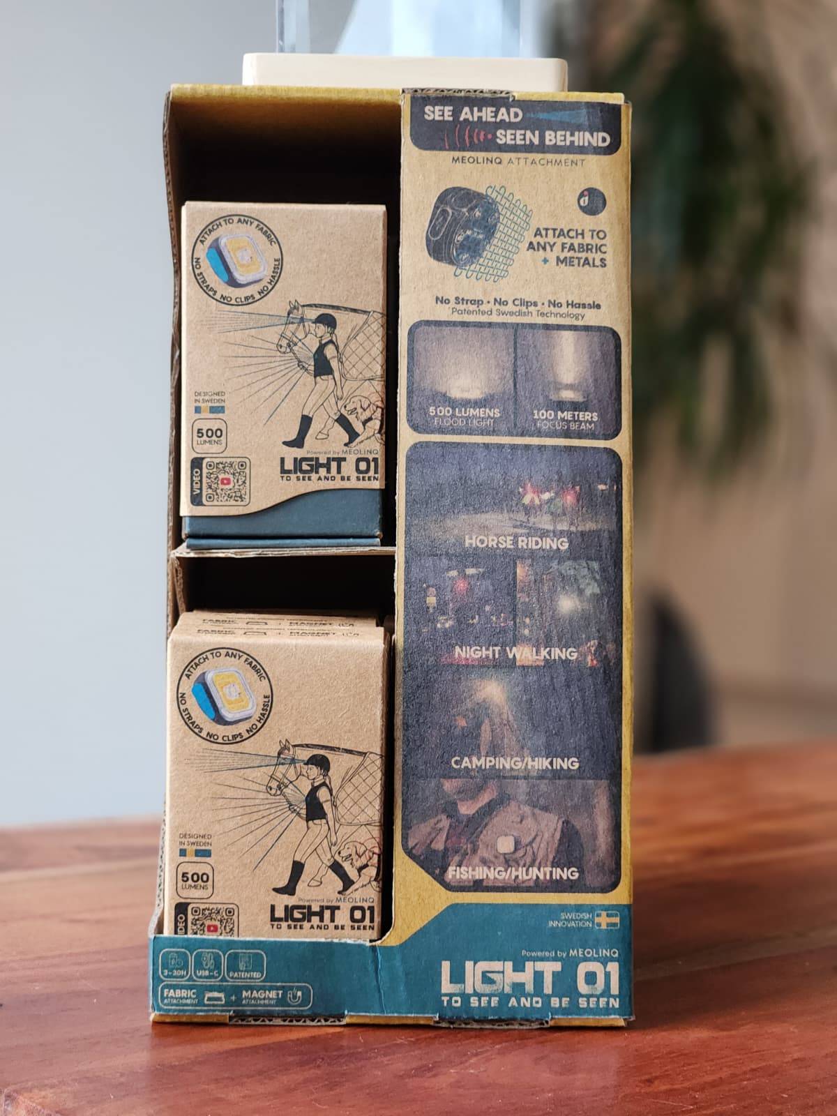 Nahaufnahme der MEOLINQ Light01 Verkaufsverpackung, die die Hauptmerkmale wie die Befestigung an Stoff und Metall hervorhebt.