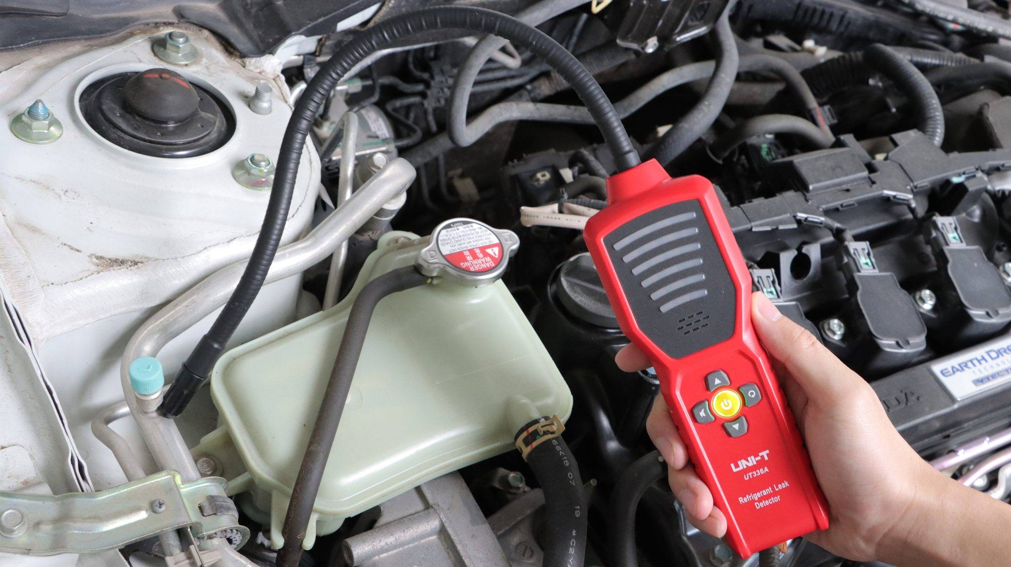 The UNI-T UT336A being used to check for leaks in a car's air conditioning system within the engine bay.