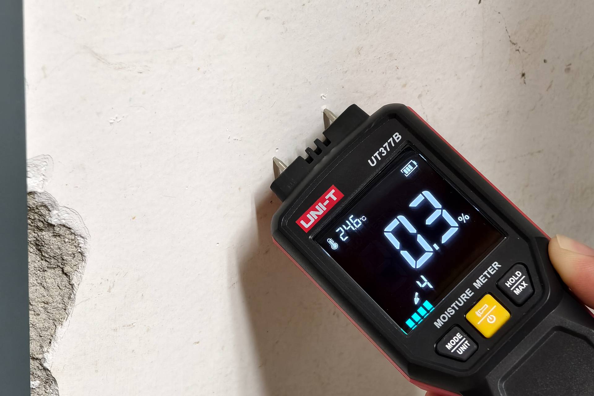 Anwendung des UNI-T UT377B zur Messung der Feuchtigkeit in einer verputzten Wand, das Display zeigt einen niedrigen Wert an.