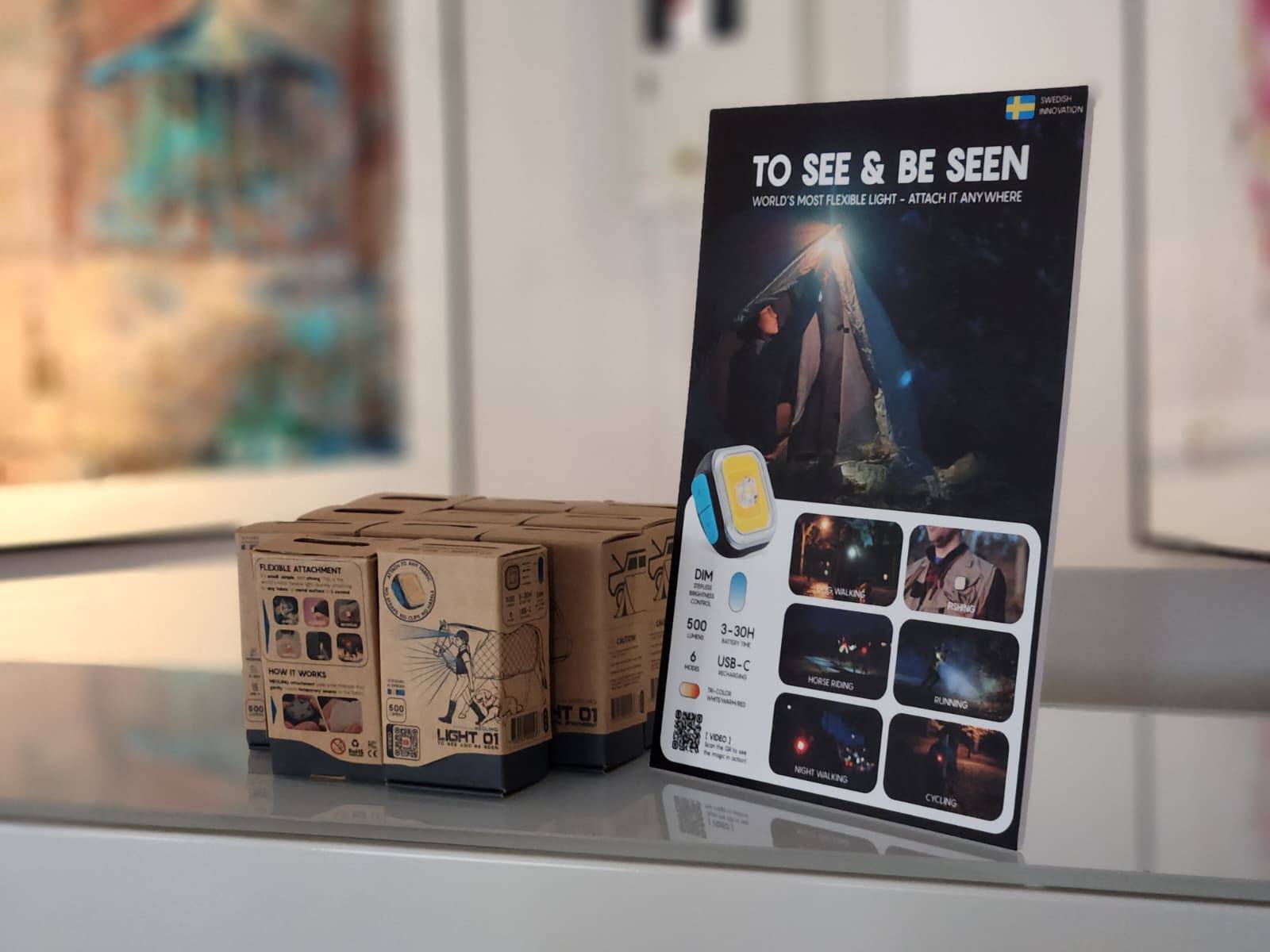 MEOLINQ Light01 Produktverpackungen und ein Werbeflyer in einer Ladenauslage oder auf einem Messestand.