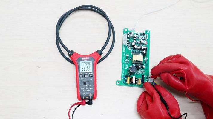 Anwendung der UNI-T UT281F Stromzange zur Messung an einer elektronischen Leiterplatte, ein Techniker trägt rote Schutzhandschuhe.