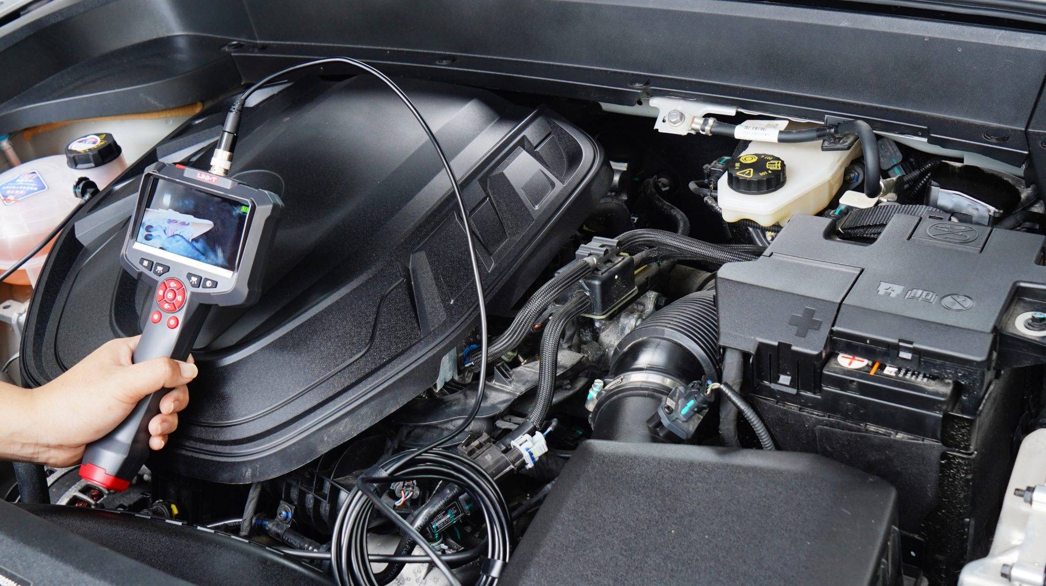 Fahrzeuginspektion mit dem UNI-T UT665P-5m: Die Sonde wird in den Motorraum eines Autos eingeführt.
