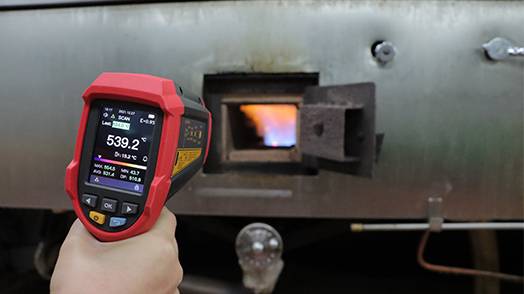 The UT305C+ infrared thermometer in industrial use, measuring the high temperature of a furnace, demonstrating its extreme measurement range up to 2200°C.