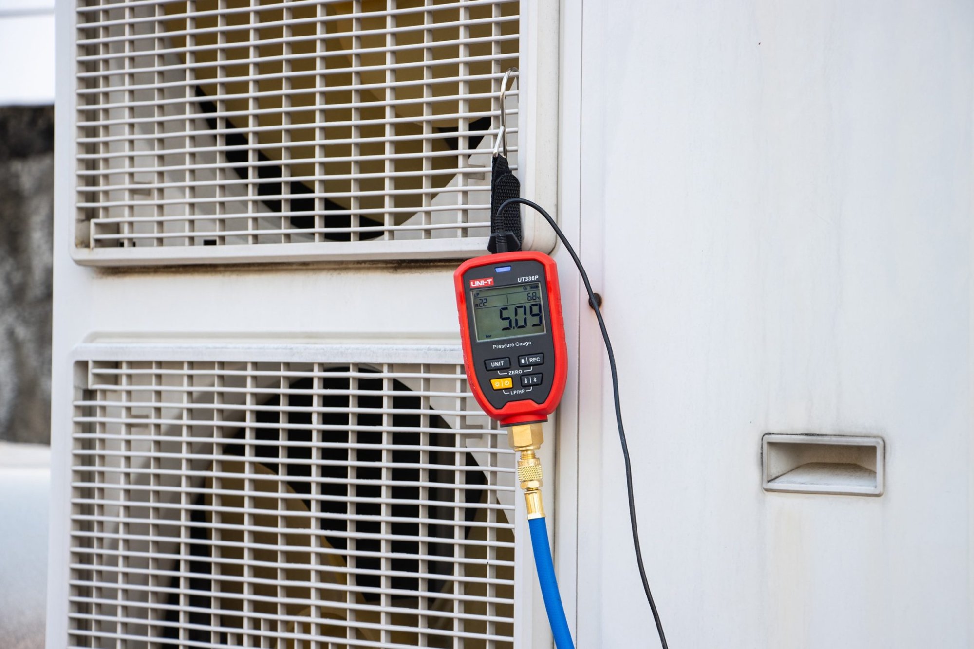 UNI-T UT336P KIT Druckmessgerät am Lüftungsgitter einer Wärmepumpe im Außeneinsatz montiert.